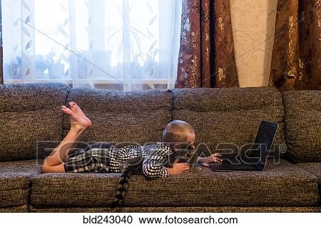 Caucasian boy laying on sofa with cat using laptop View Large Photo Image Stock Image - Caucasian boy laying on sofa with cat using laptop. Fotosearch