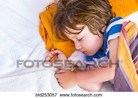 Stock Photo - Caucasian boy laying on towels sleeping. Fotosearch