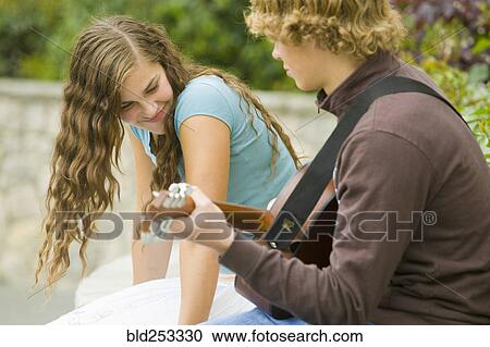 Stock Image - Caucasian boy playing guitar for girl. Fotosearch