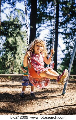 Caucasian boy pushing sister on playground swing View Large Photo Image Stock Photography - Caucasian boy pushing sister on playground swing. Fotosearch