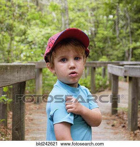 Stock Image - Caucasian boy scratching shoulder in park. Fotosearch