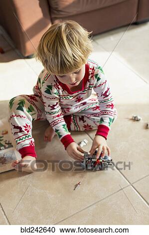 Caucasian boy sitting on floor in pajamas playing with toys View Large Photo Image Stock Image - Caucasian boy sitting on floor in pajamas playing with toys. Fotosearch