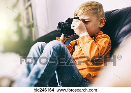 Caucasian boy sitting on sofa using camera View Large Photo Image Picture - Caucasian boy sitting on sofa using camera. Fotosearch