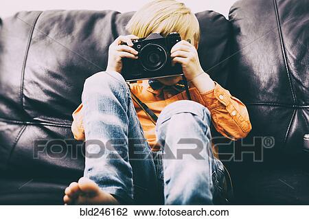 Caucasian boy sitting on sofa using camera View Large Photo Image Stock Image - Caucasian boy sitting on sofa using camera. Fotosearch
