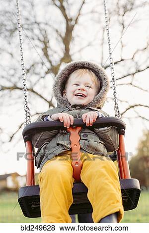 Stock Photo - Caucasian boy smiling on swing. Fotosearch
