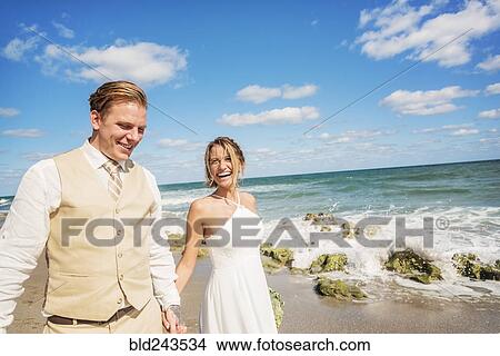 Picture - Caucasian bride and groom holding hands on beach. Fotosearch