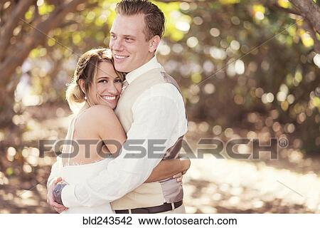 Stock Image - Caucasian bride and groom hugging outdoors. Fotosearch