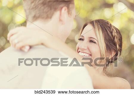 Stock Photo - Caucasian bride and groom hugging outdoors. Fotosearch