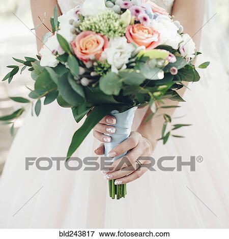 Stock Photo - Caucasian bride holding bouquet of flowers. Fotosearch
