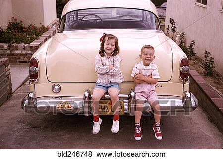 Caucasian brother and sister sitting on bumper of vintage car View Large Photo Image Stock Photo - Caucasian brother and sister sitting on bumper of vintage car. Fotosearch