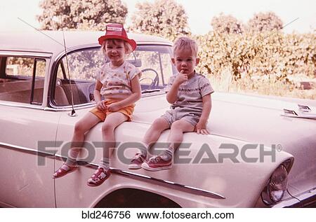 Caucasian brother and sister sitting on vintage car View Large Photo Image Stock Photograph - Caucasian brother and sister sitting on vintage car. Fotosearch