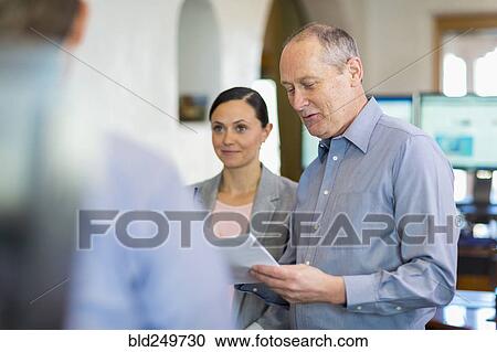 Stock Image - Caucasian business people talking in office. Fotosearch