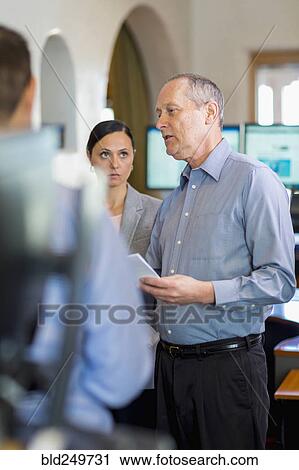 Stock Image - Caucasian business people talking in office. Fotosearch