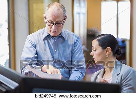 Caucasian business reading paperwork in office View Large Photo Image Stock Photography - Caucasian business reading paperwork in office. Fotosearch