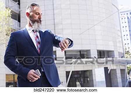 Caucasian businessman checking wristwatch outdoors View Large Photo Image Stock Image - Caucasian businessman checking wristwatch outdoors. Fotosearch