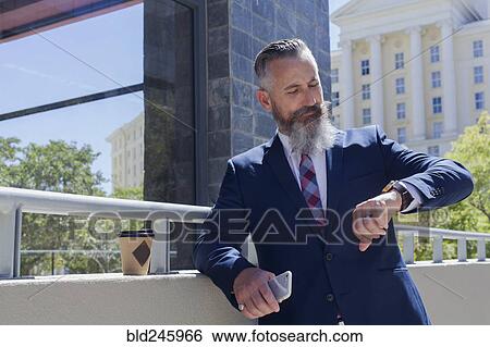 Caucasian businessman checking the time on wristwatch outdoors View Large Photo Image Stock Photograph - Caucasian businessman checking the time on wristwatch outdoors. Fotosearch