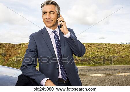 Caucasian businessman leaning on car talking on cell phone View Large Photo Image Stock Image - Caucasian businessman leaning on car talking on cell phone. Fotosearch