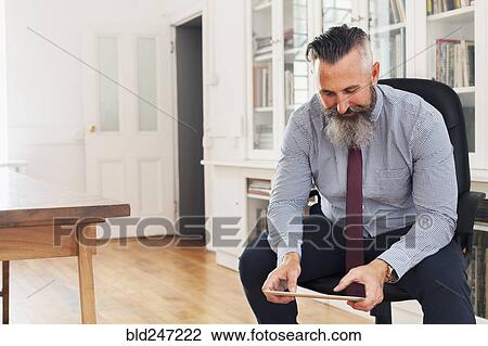 Caucasian businessman sitting on chair using digital tablet View Large Photo Image Stock Image - Caucasian businessman sitting on chair using digital tablet. Fotosearch