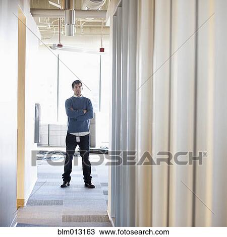 Stock Image - Caucasian businessman standing in empty office. Fotosearch