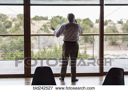 Stock Photo - Caucasian businessman talking on cell phone near window. Fotosearch