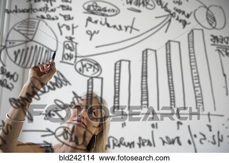 Picture - Caucasian businesswoman drawing chart on glass window. Fotosearch