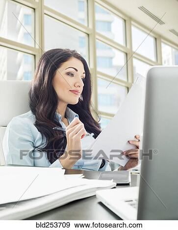 Stock Photo - Caucasian businesswoman reading paperwork. Fotosearch