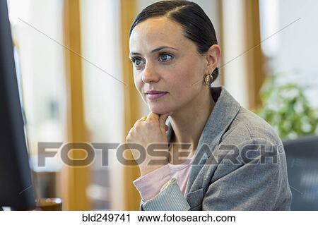 Stock Image - Caucasian businesswoman staring at computer in office. Fotosearch