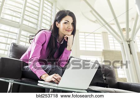 Stock Photo - Caucasian businesswoman using laptop in lobby. Fotosearch