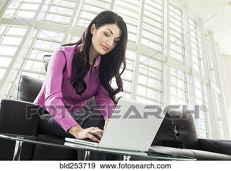 Stock Photo - Caucasian businesswoman using laptop in lobby. Fotosearch