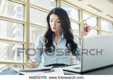 Stock Photography - Caucasian businesswoman writing on paperwork. Fotosearch