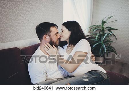 Caucasian couple cuddling and kissing on sofa View Large Photo Image Stock Image - Caucasian couple cuddling and kissing on sofa. Fotosearch