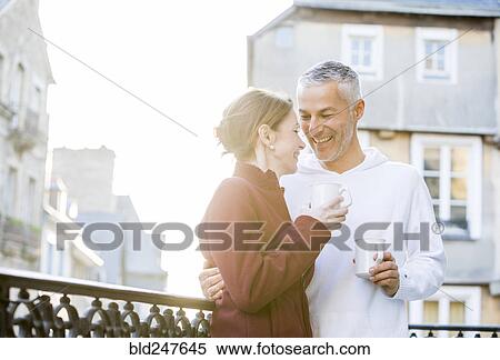 Stock Photography - Caucasian couple drinking coffee on balcony in city. Fotosearch