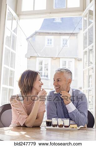 Stock Photo - Caucasian couple eating dessert near doorway. Fotosearch