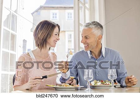 Stock Image - Caucasian couple eating salad in restaurant. Fotosearch
