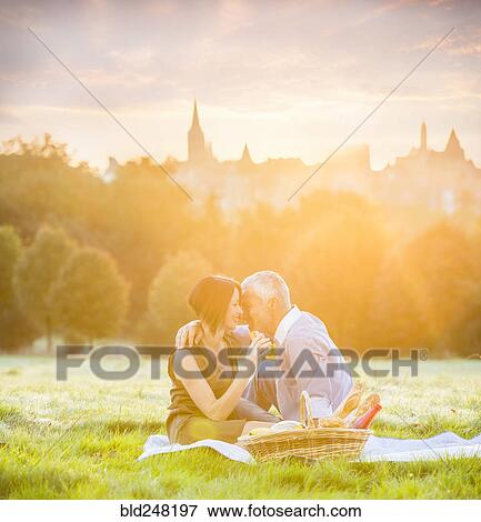 Caucasian couple enjoying picnic in grass View Large Photo Image Stock Photo - Caucasian couple enjoying picnic in grass. Fotosearch