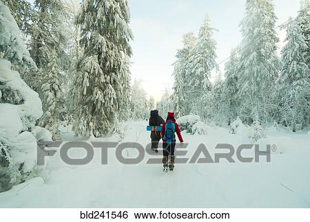 Stock Photograph - Caucasian couple hiking in snowy forest. Fotosearch