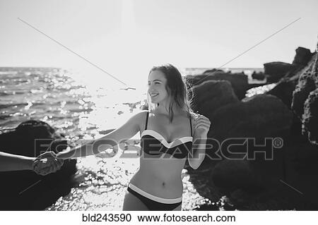 Stock Image - Caucasian couple holding hands on beach. Fotosearch