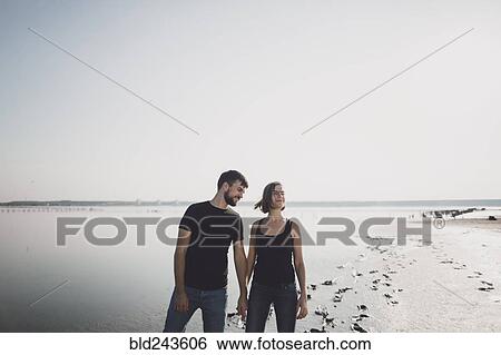 Stock Photograph - Caucasian couple holding hands on beach. Fotosearch