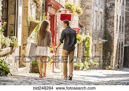 Caucasian couple holding hands walking in city View Large Photo Image Picture - Caucasian couple holding hands walking in city. Fotosearch