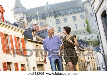 Stock Photography - Caucasian couple holding hands walking in city. Fotosearch