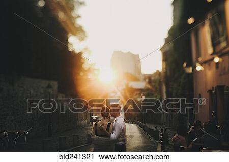 Caucasian couple hugging in city street at sunset View Large Photo Image Stock Image - Caucasian couple hugging in city street at sunset. Fotosearch