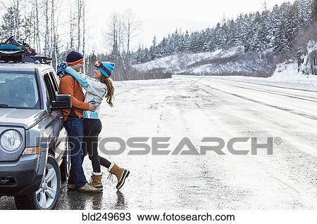 Stock Image - Caucasian couple hugging near car in winter. Fotosearch