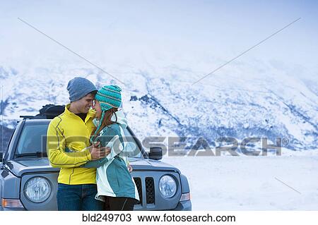 Stock Image - Caucasian couple hugging near car in winter. Fotosearch