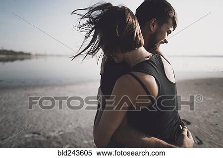 Stock Photography - Caucasian couple hugging on beach. Fotosearch