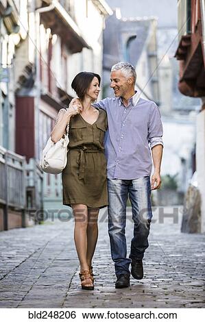Stock Photograph - Caucasian couple hugging while walking in city. Fotosearch