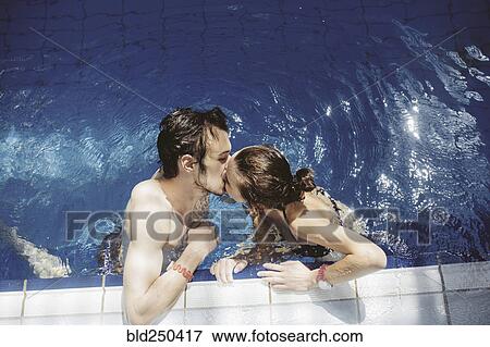 Stock Photo - Caucasian couple kissing in swimming pool. Fotosearch