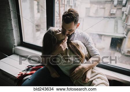 Picture - Caucasian couple kissing on window sill. Fotosearch