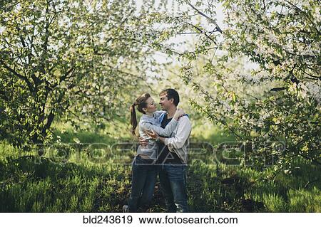 Stock Photo - Caucasian couple kissing under flowering trees. Fotosearch