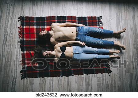 Stock Image - Caucasian couple laying flat on plaid blanket. Fotosearch