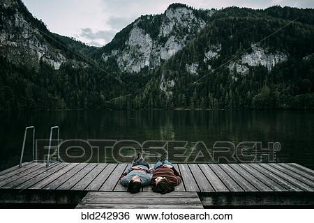Caucasian couple laying on dock near scenic view of mountain View Large Photo Image Stock Photograph - Caucasian couple laying on dock near scenic view of mountain. Fotosearch
